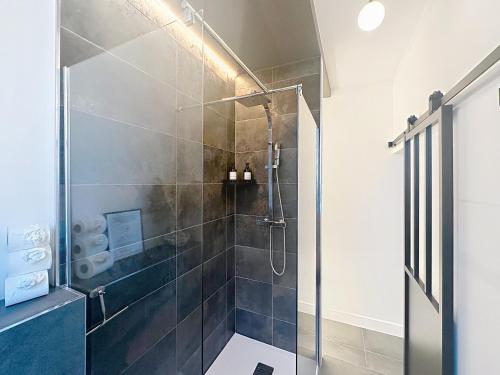 un bagno con doccia con porta in vetro di So Guest, Clou dans le fer, modern suite near cathedral a Reims