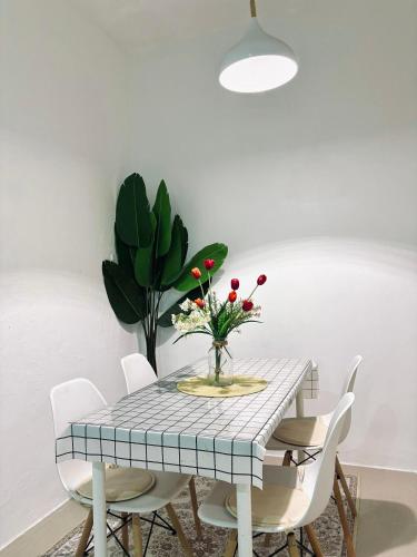 a dining room table with white chairs and a vase of flowers at JRC Homestay Kerteh in Kemaman