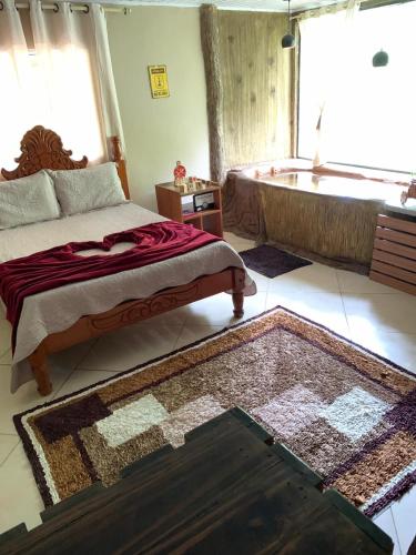 - une chambre avec un lit, une baignoire et un tapis dans l'établissement Chalé Imperial, à Santa Leopoldina