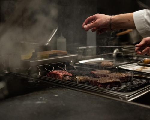a person is cooking meat on a grill at Ahlgrens Hotell Bed & Breakfast in Gävle