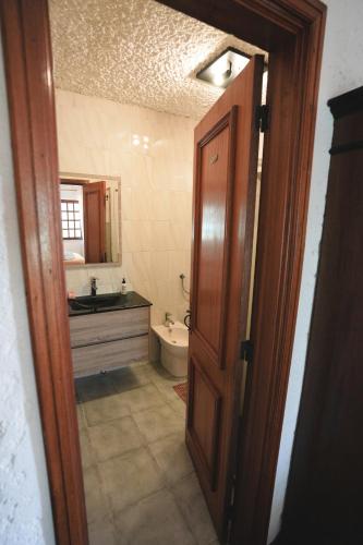 a bathroom with a sink and a toilet and a door at Refúgio da Caniçada - T4, Piscina Aquecida (Gerês) in Geres