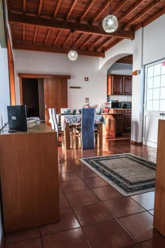 a living room with a table and a kitchen at Fun and Fly House in Praia da Vitória