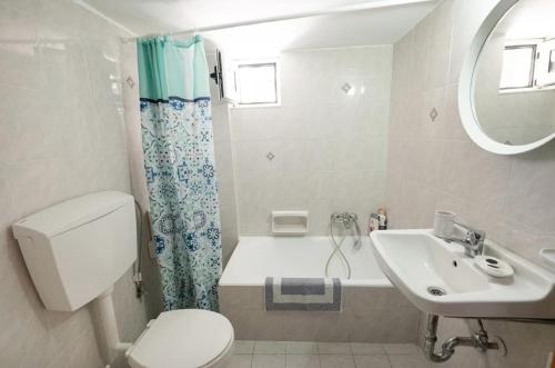 a bathroom with a toilet and a sink and a tub at Kanali seaside apartment Poros 1 in Poros