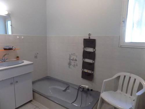 La salle de bains est pourvue d'une baignoire, d'un lavabo et d'une chaise. dans l'établissement Vaux sur Mer - MAISON INDIVIDUELLE - Domaine des Fées - Plage de Nauzan, à Vaux-sur-Mer