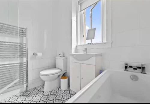 a white bathroom with a tub and a toilet at Grangeburn Residence - 2 bedroom home with parking in Falkirk