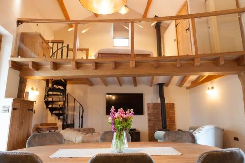 una stanza con un tavolo con fiori in un vaso di Owls Nook Barn, Luxury Barn with Hot Tub & Sauna a Sandford