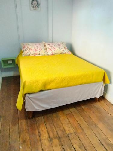 a bedroom with a yellow bed with a wooden floor at Hostal Perro Watón in Valparaíso
