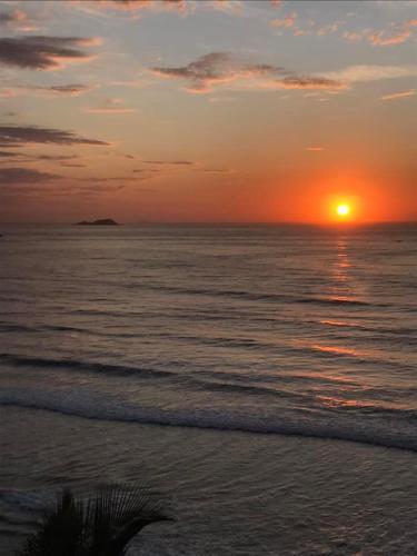 a sunset on a beach with the ocean and the sun at Pitangueiras Guarujá próximo da praia in Sao Paulo