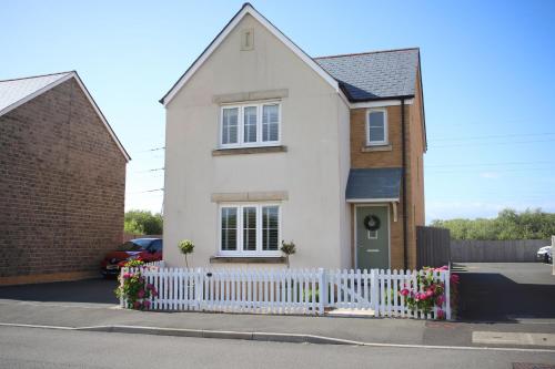 a white house with a white picket fence at Ffordd Y Meillion in Llanelli