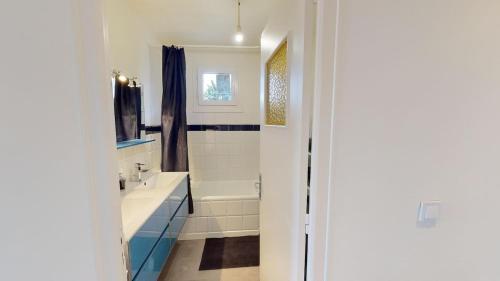 une salle de bain blanche avec une baignoire et un lavabo dans l'établissement Coloc Madia I Lot 2, à Annemasse