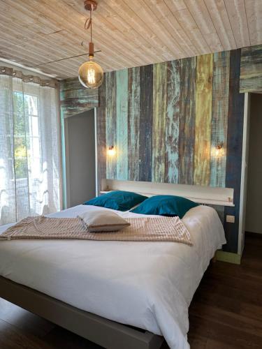 une chambre avec un grand lit blanc avec des oreillers bleus dans l'établissement chez Marie, petit cocon avec piscine, à Saint-Avit-Saint-Nazaire