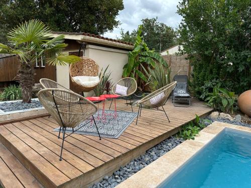 une terrasse en bois avec des chaises et une piscine dans l'établissement chez Marie, petit cocon avec piscine, à Saint-Avit-Saint-Nazaire