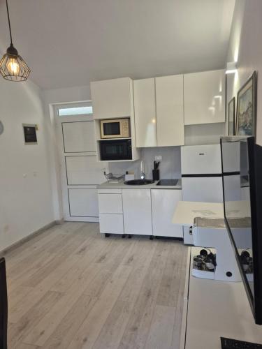 a kitchen with white cabinets and a sink and a microwave at Vidučić Apartments in Dragove