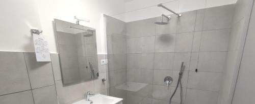 a white bathroom with a shower and a sink at Ostello Villa Monte Mario in Rome
