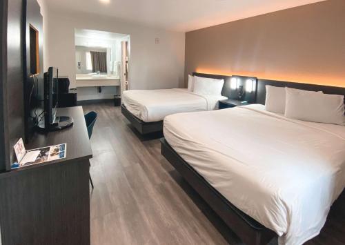 a hotel room with two beds and a flat screen tv at Studio 6 West Sacramento CA in West Sacramento