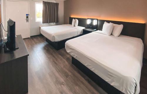 a hotel room with two beds and a flat screen tv at Studio 6 West Sacramento CA in West Sacramento