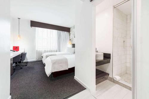 a hotel room with a bed and a desk and a mirror at The O Hotel, Trademark Collection by Wyndham in Los Angeles