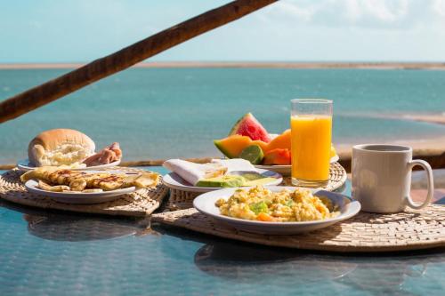 Garden House - Ilha do Guajiru في إيتاريما: طاولة مع أطباق من الطعام وكأس من عصير البرتقال