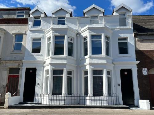 a white house with black doors on a street at The White House New York Suites in Blackpool
