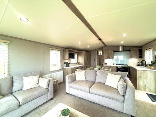 a living room with two couches and a kitchen at Skye View Lodge in Filey