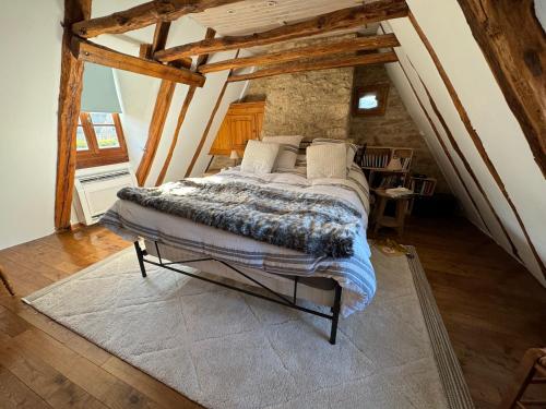 une chambre avec un lit dans un grenier dans l'établissement Le corps de Ferme et la Grange à Chassagne, à Saint-Amand-de-Coly