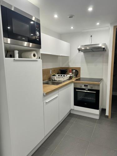 une cuisine blanche avec un évier et une cuisinière dans l'établissement Apartment Lille-Fives, à Lille