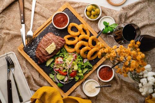 a plate of food with a sandwich and salad and onion rings at Apartamenty Rynek in Białystok