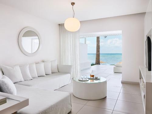 a living room with white furniture and a view of the ocean at Grecotel LUXME White in Adelianos Kampos