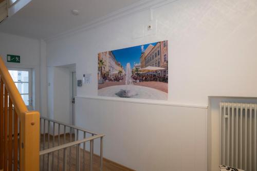 a painting of a fountain on a wall in a stairway at Cityhotel am Domplatz Self-CheckIn in Klagenfurt