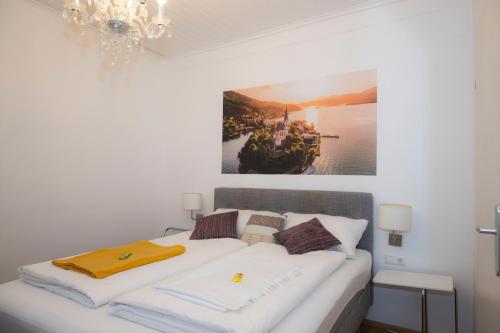 a bedroom with a white bed with a picture on the wall at Cityhotel am Domplatz Self-CheckIn in Klagenfurt