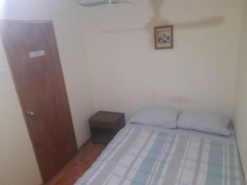 a small bedroom with a bed and a wooden door at Nuevo Hostal Consulado in Caldera