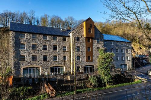 an old stone building on the side of a street at Rock Mill Studio Apartment 18 in Stoney Middleton