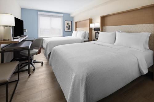 a hotel room with two beds and a desk at Holiday Inn & Suites Richmond West End by IHG in Richmond