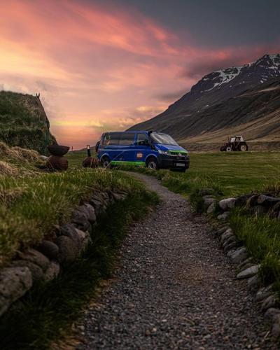 a blue van parked on a road in a field at Happy Campers - Camper van rental in Keflavík