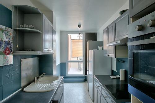 - une cuisine avec des placards bleus et blancs et un évier dans l'établissement Chic and spacious apart amaizing terrace, Évry-Courcouronnes
