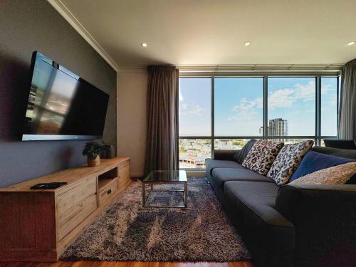 a living room with a couch and a flat screen tv at Amyra Residences at the Rowlands Apartments in Adelaide