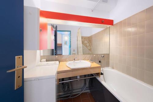 une salle de bain avec un lavabo, une baignoire et un miroir dans l'établissement AS4269 - Studio cabine direct sur plage vue mer et parking privé et numéroté, au Grau-du-Roi