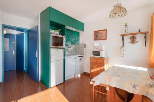une cuisine avec un réfrigérateur blanc et une table dans l'établissement AS4269 - Studio cabine direct sur plage vue mer et parking privé et numéroté, au Grau-du-Roi