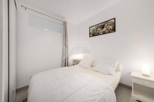 une chambre blanche avec un lit blanc et une fenêtre dans l'établissement AS17563 - P2 Entièrement équipé accès mer direct avec parking privé, au Grau-du-Roi