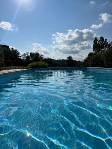 une grande piscine avec de l'eau bleue dans l'établissement Le corps de Ferme et la Grange à Chassagne, à Saint-Amand-de-Coly