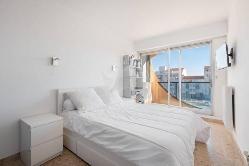 une chambre blanche avec un grand lit et une fenêtre dans l'établissement AS17006 - P3 Vue mer face à la plage sans route à traverser et proche centre ville, au Grau-du-Roi