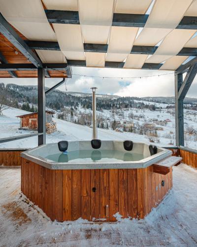 a jacuzzi tub in the snow with a view at Casa Bella Vlădeasa in Săcuieu