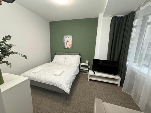 a bedroom with a bed and a flat screen tv at Gremium Apartments in Bratislava