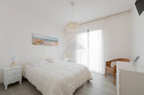 une chambre blanche avec un lit et une fenêtre dans l'établissement AS13357 - P3 face à la plage sans route à traverser, proche centre ville avec parking privé, au Grau-du-Roi