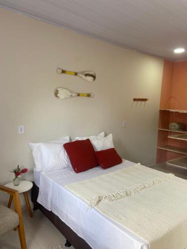 a bedroom with a bed with two red pillows at Sabiá & C0 Casa Hotel Suítes in Prado