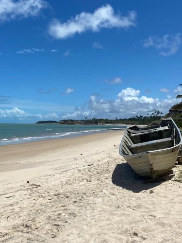 a boat sitting on the sand on a beach at Sabiá & C0 Casa Hotel Suítes in Prado