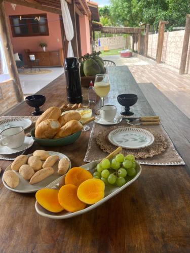 a table with plates of bread and fruit on it at Sabiá & C0 Casa Hotel Suítes in Prado
