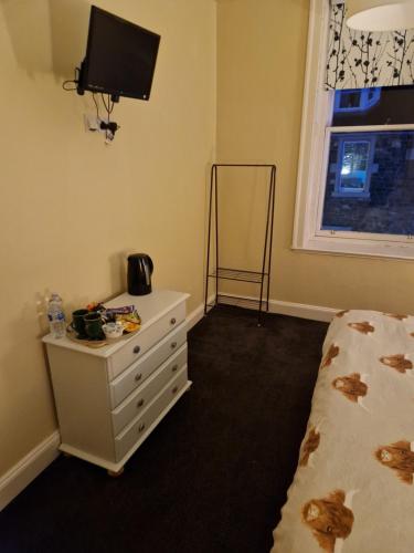 a bedroom with a bed and a tv on the wall at Neidpath Inn in Peebles