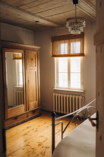 a bedroom with a bed and two windows and a wooden floor at Kalnciema kvartāla Kuldīgas rezidence in Kuldīga