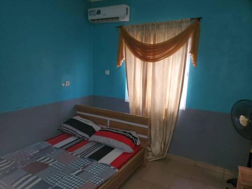 a bedroom with a bed with a curtain and a window at ATEWO HERITAGE HOTEL, ilogbo ekiti, Ekiti state in Usi
